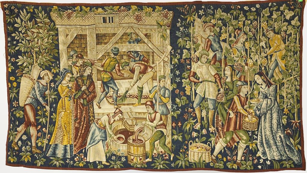 FRENCH AUBUSSON TAPESTRY WITH WINE MAKING SCENE: Tapestry depicts men and women making wine in a rural country scene amongst grape vines and flowers. In vibrant threads atop a blue background with a red border. H: 50 in. L: 80 in.