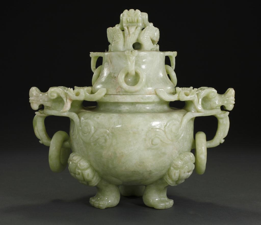 CHINESE GREEN SOAPSTONE COVERED CENSER: The globular body raised on three paw feet, two ringed dragon handles attached to the body, three ringed handles attached to the lid, surmounted by dragon. H: 9 1/8 in.