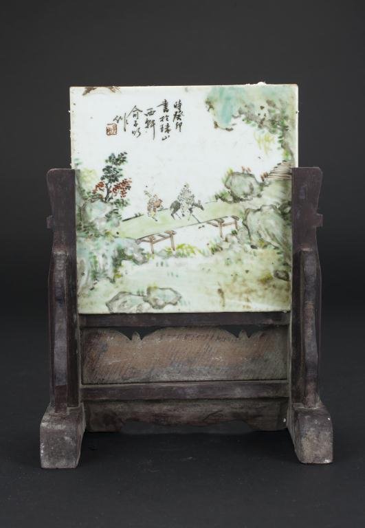 CHINESE PAINTED TILE ON WOOD STAND: Depicting a scholar riding on a donkey, followed with his servant in a mountain scene. H: 9 1/2 in.