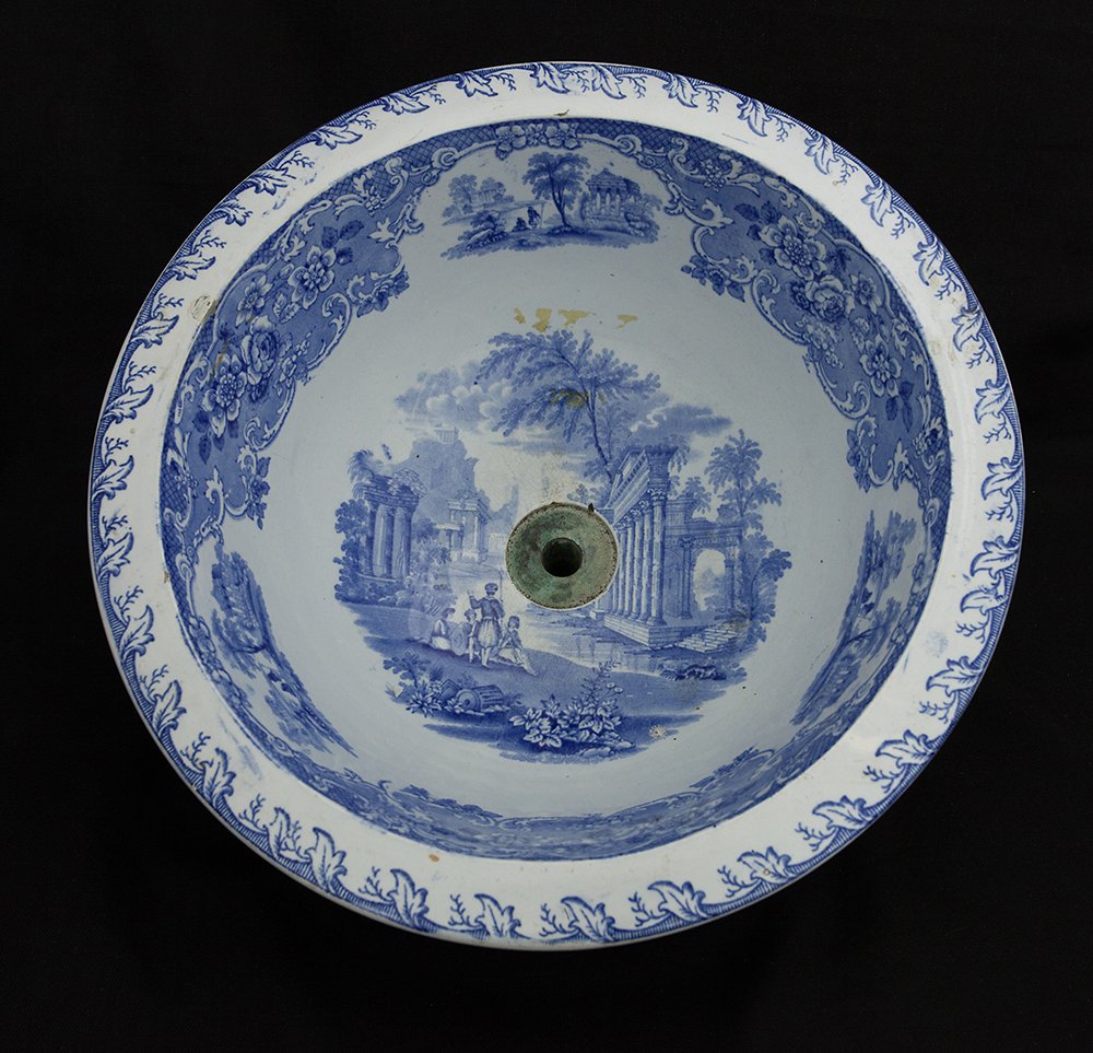 ENGLISH BLUE AND WHITE PORCELAIN SINK: The center of the interior painted with figures in a town center. The rim decorated with scrolling floral design. D: 14 7/8 in.