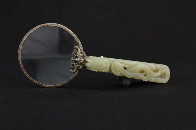 CHINESE MAGNIFYING GLASS WITH JADE HANDLE: The handle carved with a chilong and dragon; and with a silver bat attaching the jade to the magnifying glass. L: 7 3/4 in.