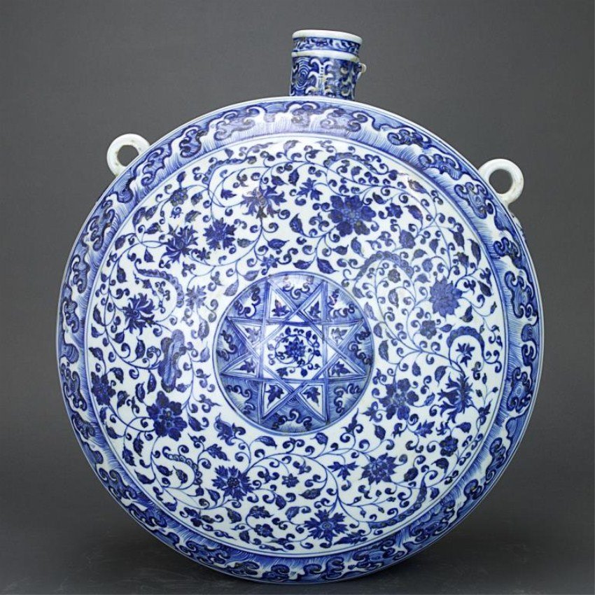 LARGE CHINESE BLUE AND WHITE HANGING MOON FLASK: With an octogram in center surrounded by dense scrolling floral pattern. Around the outer rim, a thin band of wave design. D: 17 in. H: 7 1/2 in.