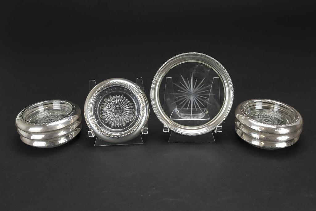 EIGHT SILVER AND GLASS COASTERS: The glass of each etched with a varying starburst design and with a silver border. D: 3 7/8 in.