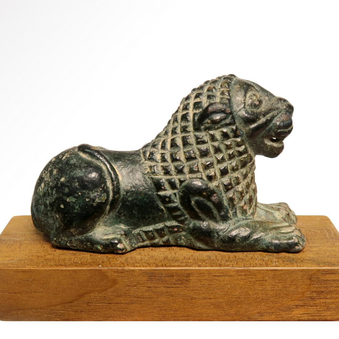 Rare Assyrian Bronze Lion, c. 4th Millennium B.C.: Rare Assyrian Bronze Lion, c. 4th Millennium B.C. Bronze figure of a reclining lion with erect head and extended forepaws, tail curled to the side, cross-hatched mane, lentoid eyes and raised nasal-li