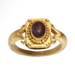 Roman Gold and Garnet Ring, c. 300 A.D.: Roman Gold and Garnet Ring, c. 300 A.D.Solid gold ring, the upper rectangular bezel inserted with a cabochon garnet surrounded by granules, the shoulders fashioned in a scroll pattern. Exquisite.Size: