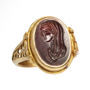 Roman Gold Ring with Garnet Intaglio, Bust of a Lady, c. 2nd Century A.D.: Roman Gold Ring with Garnet Intaglio, Bust of a Lady, c. 2nd Century A.D.Solid gold with wide shoulders nicely carved in open work with floral pattern, the bezel set with a cabochon garnet engraved