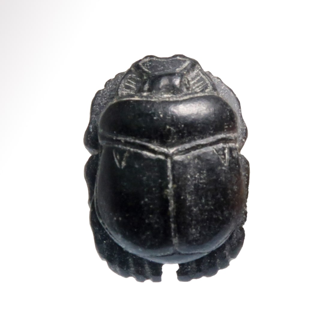 Egyptian Black Steatite Scarab, c. 1200-1000 B.C.: Egyptian Black Steatite Scarab, c. 1200-1000 B.C. Realistically carved with extremely fine incised details. Wide ribbed loop at the base for suspension. Exquisite. Size:2.4 cm L - 15/16 inch Material:
