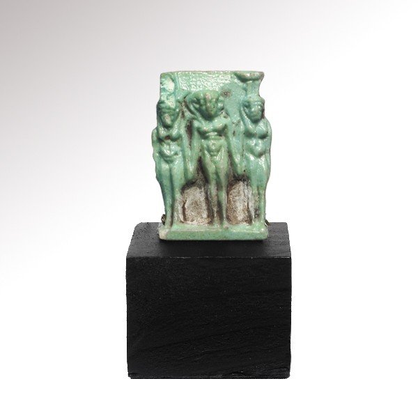 Turquoise Faience Triad Amulet , c.500 B.C.: Turquoise Faience Triad Amulet of Isis, Nephthys and Horus,c.500 B.C. Horus-the-child flanked by Isis and Nephthys all holding hands and naked. With suspension loop at back. Material: