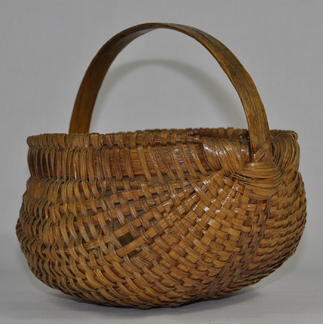 Native American Antique Melon Form Splint Basket: New England, carved bentwood handle continuing through the body, overall fair condition ( five breaks counted) shellacked, 8.75 in. x 9.75 in.