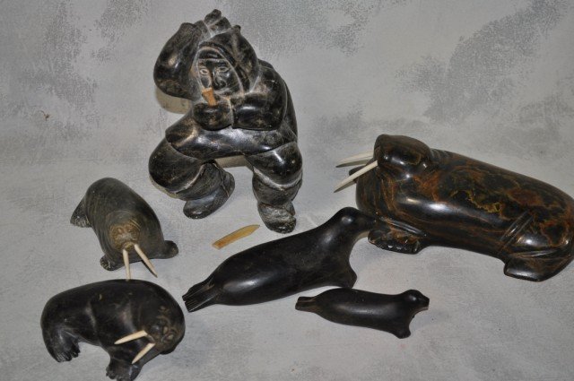 Inuit Stone Carvings, 6pcs: Some chips present except for smallest, figure of a man carrying a bird and large green stone walrus have been repaired, tallest figure stands H 6"