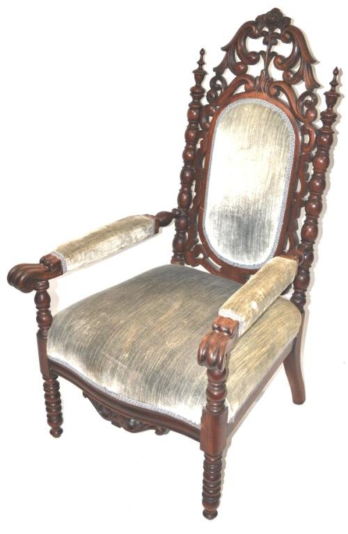 Antique Victorian Baroque Open Armchair: Elaborately detailed and highly accomplished pierce-carved upper crest surrounding an oval back flanked by baluster-turned stiles, featuring upholstered and padded arms, scrolled palm rests, and suppo