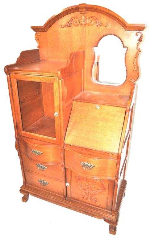 Lexington Golden Oak Side by Side: Arched molded cornice surmounting a plinth with applied carving and housing a shaped mirror above a slant-front desk opening onto a fitted interior; over one drawer and one relief-carved door; on the 