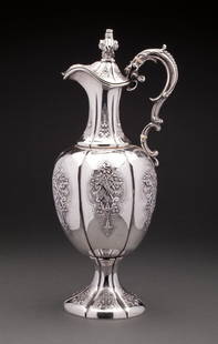 FINE VICTORIAN SILVER CLARET JUG: LONDON, 1854, Robert Hennell III. The fluted pyriform body embossed with foliate cartouches, mounted with a scrolling handle, hinged cover and spreading base. 15 in, 38 cm, high 990 gr.