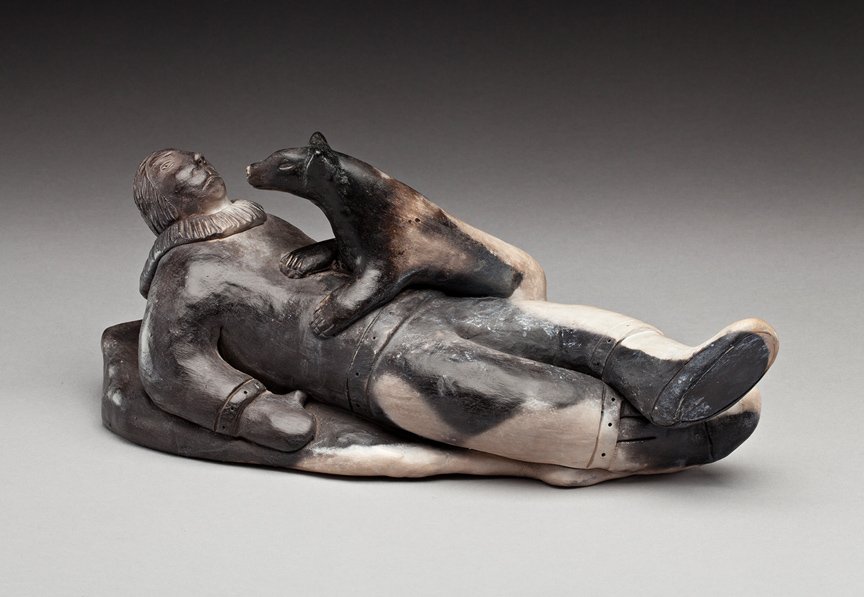 Roger Aksadjuak (1972-): Rankin Inlet, Reclining Man and Dog, ca. 2005, ceramic, signed "ROGER AKSADJUAK SILU", 4.5 x 10.75 x 4.75 in, 11.4x27.3x12.1 cm. --- CATEGORIES: Inuit, Eskimo