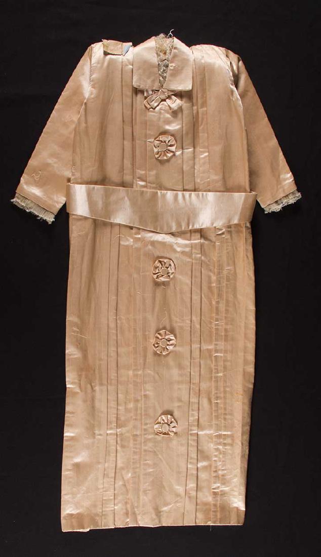 CHILD'S CASKET ROBE, EARLY 20TH C: Beige satin, dress front only, collar w/ bow & 4 cockade faux buttons, L 38", excellent.