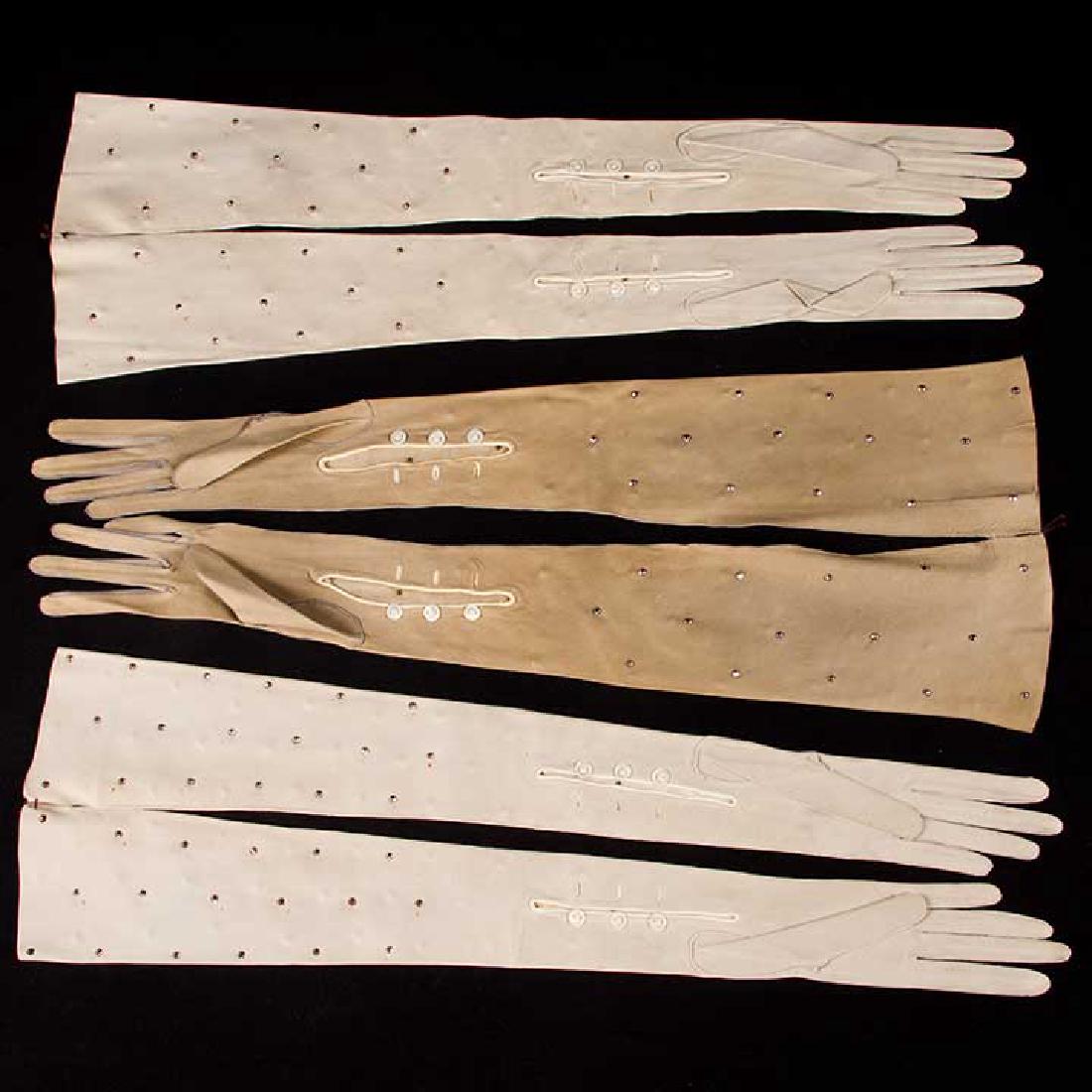 FOUR PAIR LADIES LEATHER OPERA GLOVES, 1890-1910: All unworn: 1 pair cream kidskin w/ gold tambour embroidery & gold silk ribbons, L 27", (couple stains & nicks); 3 pair grey fine suede w/ faceted small steel studs, L 22.5", (2 pair w/ few tiny rust 