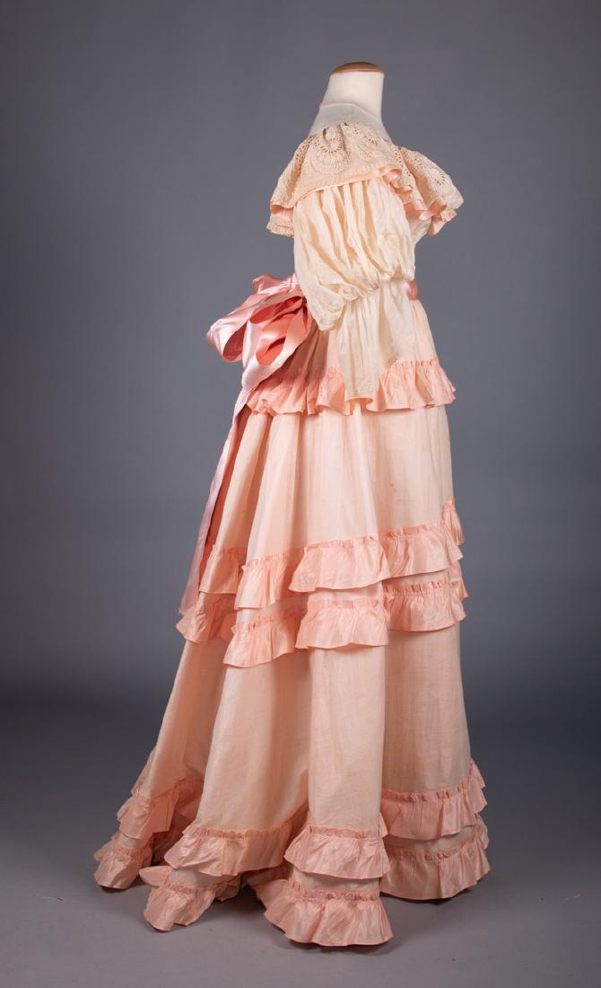 CREAM & PINK TEA GOWN, 1890s: 2-pc off the shoulder neckline w/ embroidered collar & puff sleeves, ribbon flounced skirt, wide silk sash, labeled â€œMme. Keily, NYâ€, B 34â€, W 22â€, Skt L 45-48â€, (stain at CF nec