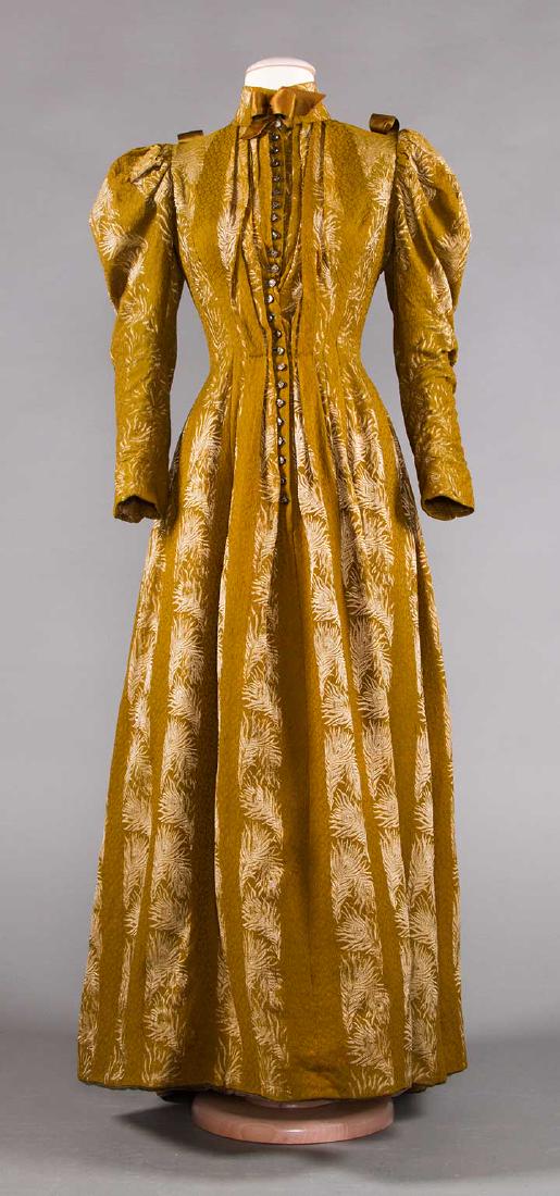 WOOL BROCADE DAY DRESS, MID 1890s: 1-pc olive green w/ cream peacock feather brocade stripes, 23 small steel CF buttons, (small mend on skirt, tear near hem) very good.