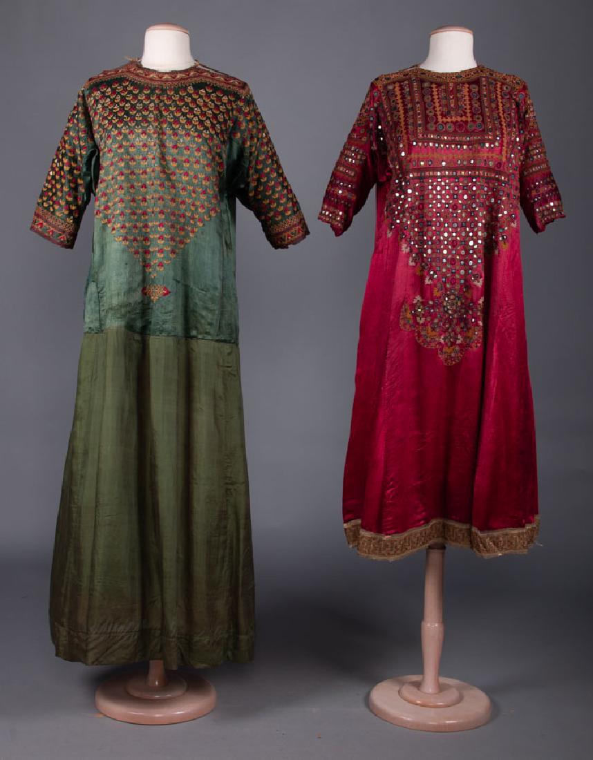 TWO EMBROIDERED SILK DRESSES, PAKISTAN, EARLY 20th C: Both silk satin: 1 green w/ gold & red embroidered bodice, B 44", L 54", (period mends at CF lap, underarm silk worn, skirt not original, some fraying); 1 red w/ multicolor embroidery & round mirrors,