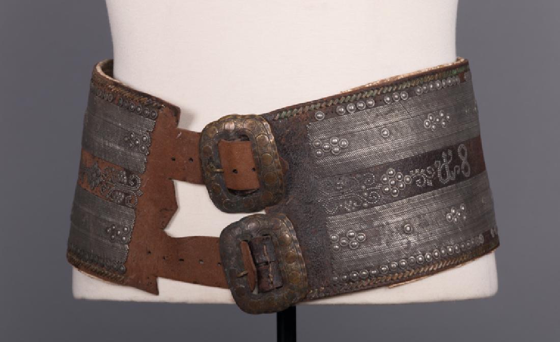 WIDE LEATHER & METAL ETHNIC BELT: Dark brown leather w/ silver metal bands & rivets pair front buckles, L 37-40", WD 6", (missing rivets, oxidization, leather worn) fair; t/w 1 faded red caftan w/ metallic gold embroidery.