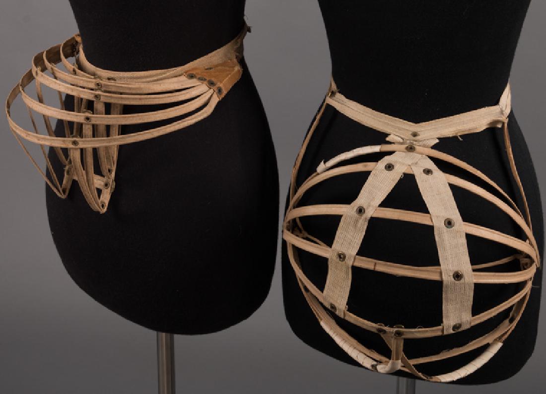 TWO COLLAPSIBLE BUSTLES, 1880s: Both w/ brass rivets: 1 tan w/ leather, (leather tabs detached, W band shredding) very good; 1 melon shaped, (W band torn, 4 areas of ribs reinforced w/ tape) fair; t/w 1 collapsible bustle (stained).