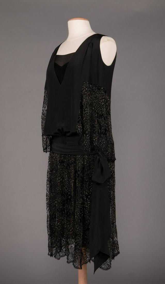 FIREWORK BEADED LACE PARTY DRESS, 1920s: 2-pc firework motif party dress in black silk w/ silver beaded lace, blouson top w/ deep V-neck & self belt, skirt attached to slip, H 36", L 45", (bead loss, broken net, 3" repair to net at right und
