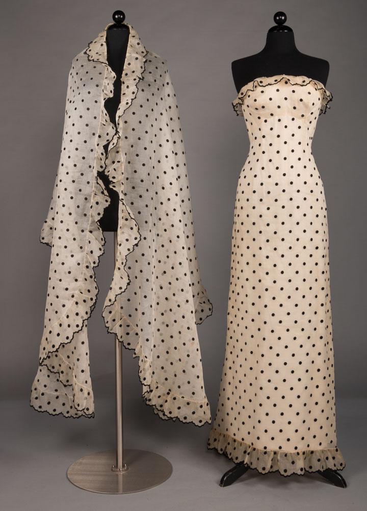 BALENCIAGA COUTURE EVENING ENSEMBLE, PARIS, 1960: Strapless evening sheath in silk gazar w/ black embroidered polka dot, scalloped trimmed B gathered in plunging V-back to trained & ruffled skirt, CB bow & matching shawl, built in boned corset & silk