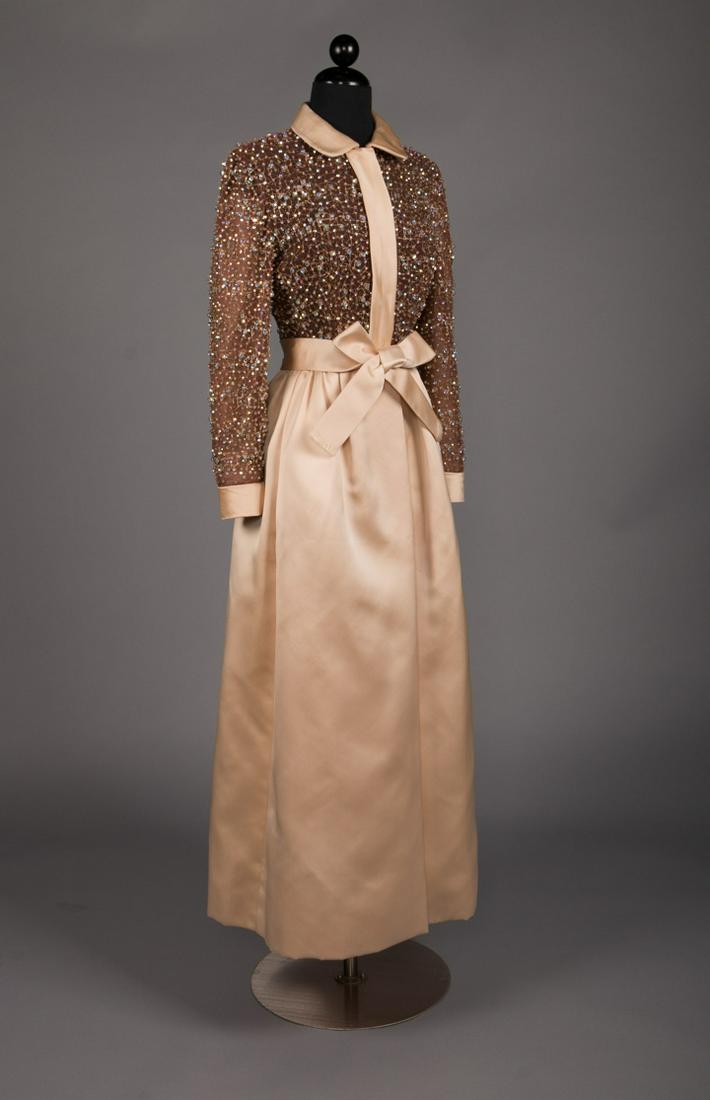 GEOFFREY BEENE BEADED EVENING GOWN, 1960s: Late 1960s evening gown w/ cream satin skirt, peter pan collar, self belt & cuffs & brown silk chiffon bodice w/ all-over gold thread beading & rhinestones, label "Geoffrey Beene", B 34", W 24", L 52"