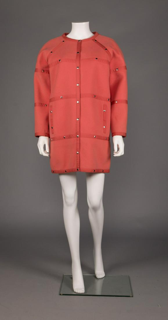 COURREGES WOOL COAT, PARIS, 1970s: Shrimp pink wool blend coat w/ canvas piping accented w/ silver snaps, CF opening, raglan sleeve, 2 slit pockets at front Hs, label "Courreges, Paris", B 34", L 33", (light spots at B, snacks at right