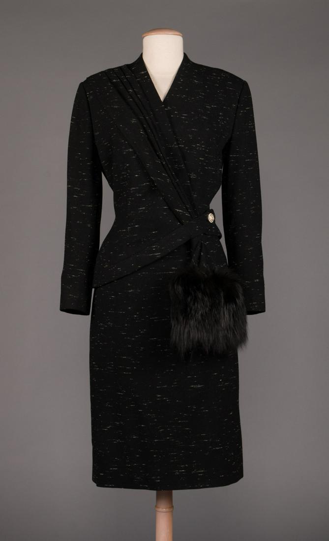 LILLI ANN BLACK WOOL & FUR TRIMMED SKIRT SUIT, c. 1950: Long sleeve afternoon skirt suit in black wool flecked w/ white, asymmetric jacket w/rhinestone button closure at left H & self scarf w/ fur trim, 3/4 length skirt, "Lilli Ann", B 38", W 25", SKt L 26