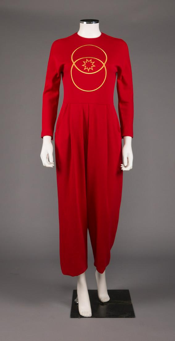GEOFFREY BEENE EMBROIDERED JUMPSUIT, 1980s: Red wool jersey jumpsuit w/ slash pockets at pleated W, long sleeves w/ zippers at inside cuff, CB zip closure, wide leg & interlocking ring & star embroidery in gold to chest, label "Geoffrey Beene",