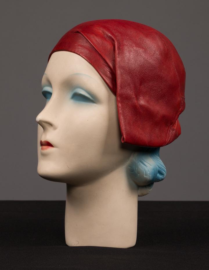 CALLOT SOEURS LEATHER CLOCHE, PARIS, c. 1925: Oxblood red leather cloche w/ fold under tucked detail at left ear & silk lining, label "Callot Soeurs, Paris", (slightly dirty, some stretching at nape of neck) very good.