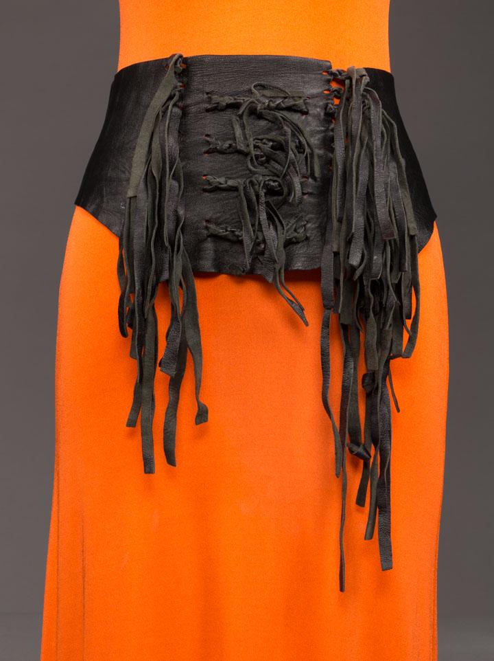 STEPHEN BURROWS CORSET BELT, LATE 1960s: 1 Stephen Burrows c. 1968-1969 black leather corset belt w/ fringe, cut away across Hs, lace up closure at front left, label "O Boutique", W 28" & up, HT 3"- 7", excellent; t/w leather knotted wrap be