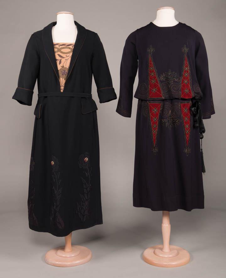 TWO TUNIC STYLE WOOL TWILL DAY DRESSES, c. 1919: 1 black w/ tan metallic brocade B insert, self belt, brown piping to collar, cuffs & faux H pockets, embroidered florals at hem w/ ombre centers, B 40", W 40", L 50", (tiny stains CF, snacks CF W & le