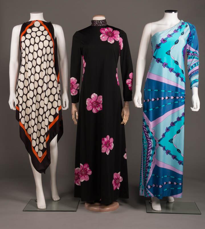 THREE MULTICOLORED OR FLORAL DRESSES, AMERICA, 1970s: 1 printed silk oversized handkerchief dress in brown, white & orange w/ single button closure at both SHs, monogram in print, labeled "Estevez, Resort/Sport", B 48", L 31-50", (stains, holes at L unde