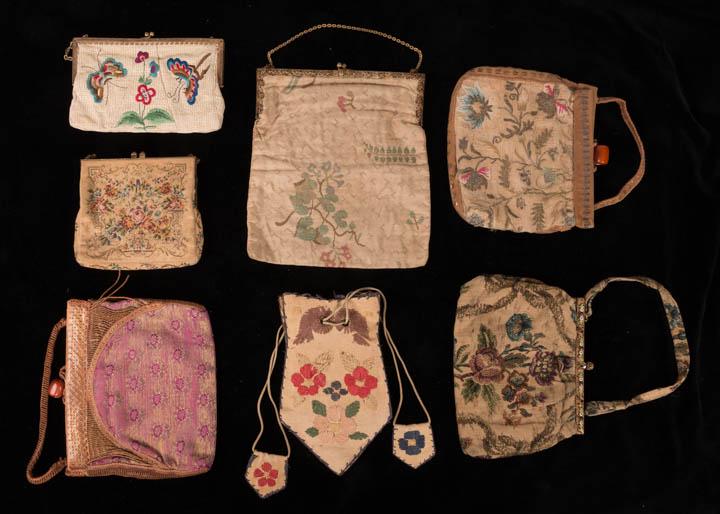 SEVEN HANDBAGS, 1920-1930s: 1 pettit point embroidered w/ carnelian clasp, "Made in Austria", L 5.5", W 6"; 1 woven tan w/ sparse floral & foliate motif, W 8.5", L 9.5", (stained); 2 w/ leather cover frames & handles, Baltic amb