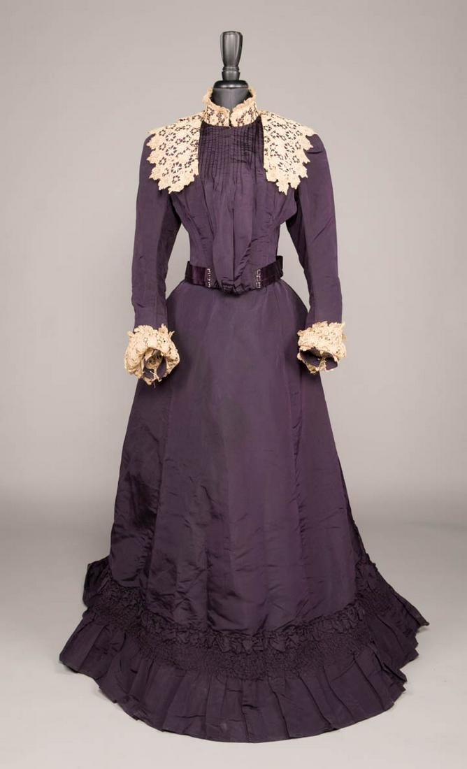 SILK FAILLE VISITING GOWN, 1890s: 2-pc aubergine silk faille visiting gown w/ large circular renaissance style chemical lace collar w/ front lappets & cuff, bodice w/ vertical tucks into mono bosom full front & satin ribbon W w/ minia