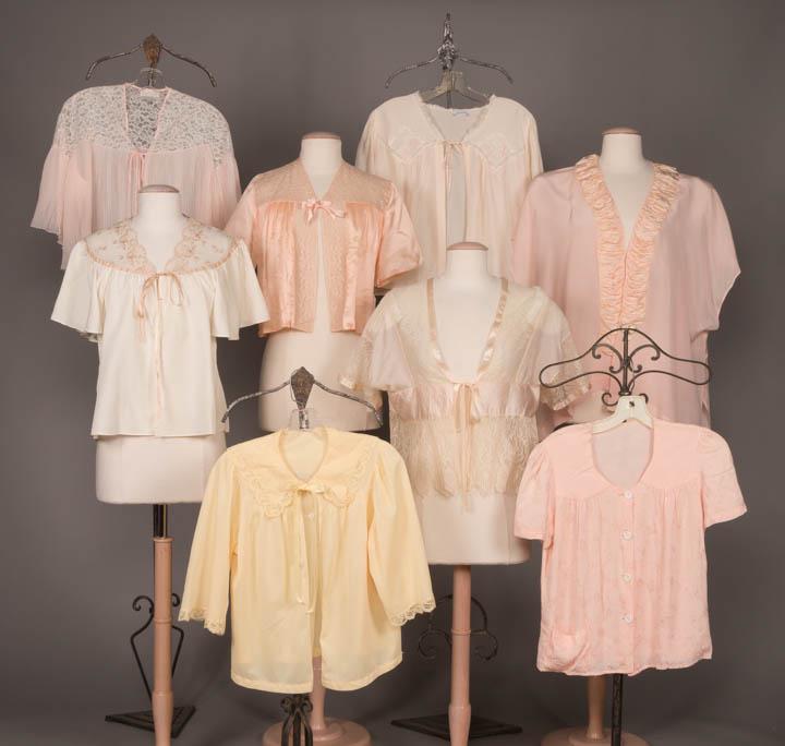 EIGHT BED JACKETS, c. 1912 & 1930-1950s: 1 cream w/ tan lace SHs, B 46", L 20.5", (fraying at edges of lace); 1 white w/ pink embroidery, label "Styled by Josie", B 44", L 21"; 1 pink w/ white buttons, B 39", L 22"; 1 yellow, B 44", L 22"; 1