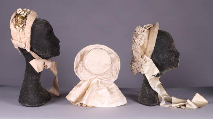 THREE LADIES BONNETS, 1830s & 1870s: 1 patterned ivory silk spoon bonnet florals, trimmed w/ wax paper buds & cloth leaves, 1870s, brim circumference 16", (dirty, spot stains throughout, lining shattering) good; 1 exceptional cream silk 
