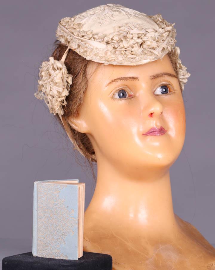 EUGENIE BONNET, AMERICA, 1860s: Bonnet of fine wool twill w/ silk floss embroidered floral sprig at crown trimmed w/ silk blond lace & fine silk pico edged ribbon festoons at temple, circumference 17", (discoloration & light stainin