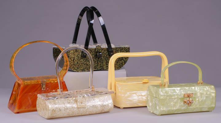 FIVE LUCITE HANDBAGS, AMERICA, 1950s: 1 bakelite w/ carved flowers & leaves, 8"x4.5"x9"; 1 pearlescent w/ gold confetti inlay & clear cut radiating floral lid, c. 1957, label "Gilli Originals, New York" featured in "Carry Me", page 44-45,