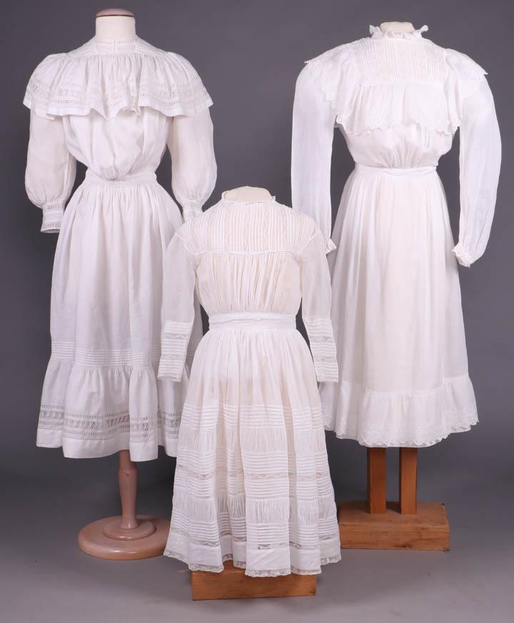 THREE YOUNG LADIES SUMMER FROCKS, c. 1905: 1 cotton lawn dress w/ vertically tucked yoke & chevron tucking to back bodice w/ lace insertion to entire yoke, horizontal rows of tuck, lace insertion & ruching to skirt, CB MOP button closure, B 31