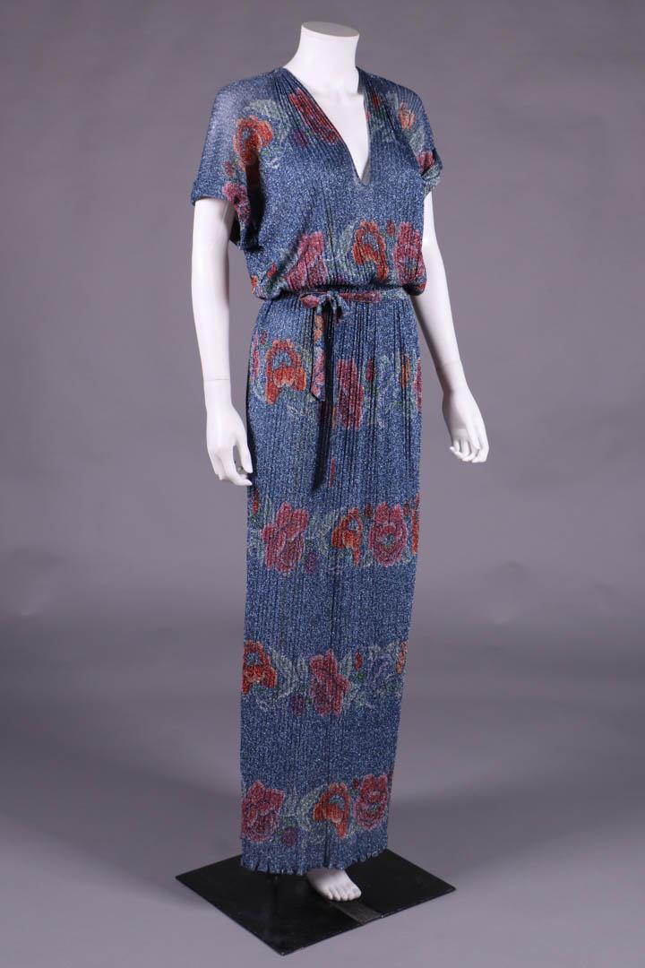 MISSONI LAMÉ FLORAL PARTY DRESS, ITALY, 1970s: Ribbed knit Egyptian inspired faux pleated party dress w/ Chinoiserie inspired horizontal floral bands on steel blue ground, short dolman sleeve w/ fold over epaulet tab at top SH, plunging V-neck, ga