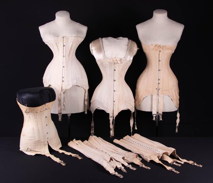 FIVE CORSETS, AMERICA, 1910s: 1 lace w/ ribbon insertion, B 30", W 19", L 15.75"-20", (laces N/I, discoloration, straps stained); 2 w/ lace & ribbon insertion & label "American Beauty, TM Reg. U.S. Pat. Kalamazoo Corset Co. Maker"