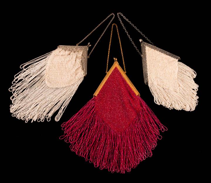 THREE DIAMOND SHAPED FRINGE BAGS, 1910-1930s: All w/ deep looped fringe: 1 crocheted w/ ruby colored beads & gold tone frame in geometric guilloché motif lined in cherry silk crepe & silk velvet ribon, 7" x 14.5", (tarnish to frame, fabric bunch