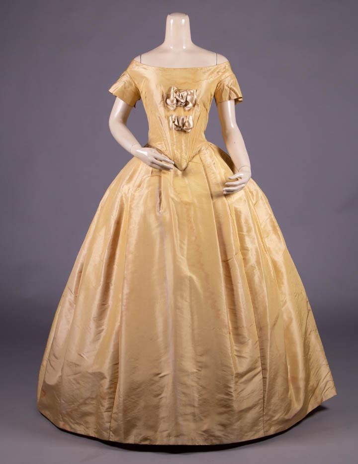 YELLOW SILK EVENING GOWN, c. 1850: 2-pc gown of ribbed yellow silk taffeta w/ broad scoop neck, short tube sleeves, lightly boned bodice w/ deep triple darts to CF V-waist, CB lacing, wide bell skirt w/ deep knife pleated gathers from 