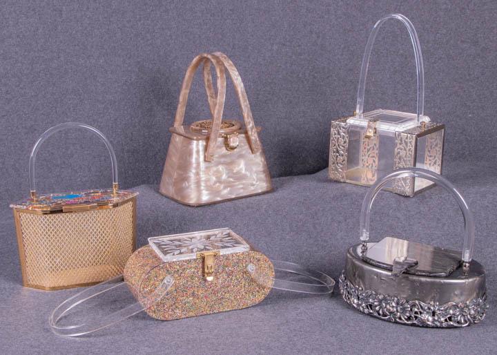 FIVE LUCITE HANDBAGS, AMERICA, 1953-1960: 1 dark grey pearlescent w/ silver metallic floral frame to bottom edge & clear handle, 1953-1957, stamped Â“Llewellyn Inc, NYCÂ”, 8.5Â” x 6.5Â” x 4Â”, (tarnish to frame); 1 rectangular 