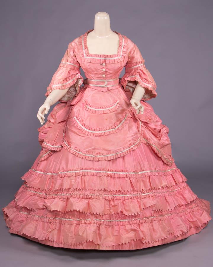 FOUR PIECE PINK SILK TAFFETA BALL GOWN, c. 1872: Bubblegum pink 4-pc gown c/o bodice, belt, over skirt & trained full skirt, bodice w/ square neckline, white silk covered & needle embroidered CF button closure, engageante sleeve cuff, polonaise over