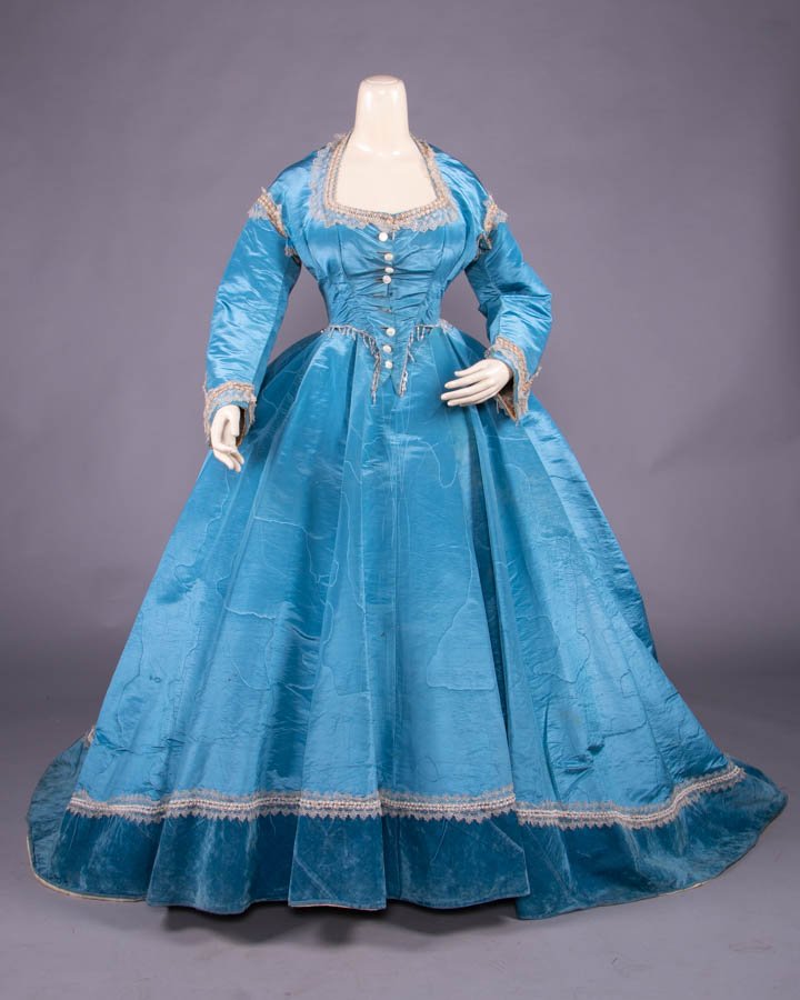 CONVERTIBLE CERULEAN BLUE SILK MOIRE GOWN, c. 1866: 3-pc blue cerulean blue silk moiré gown w/ dinner bodice & trained skirt trimmed w/ serpentine cording w/ crystal & white seed bead rosettes & blond silk lace, gored skirt w/ broad silk velvet hem ba