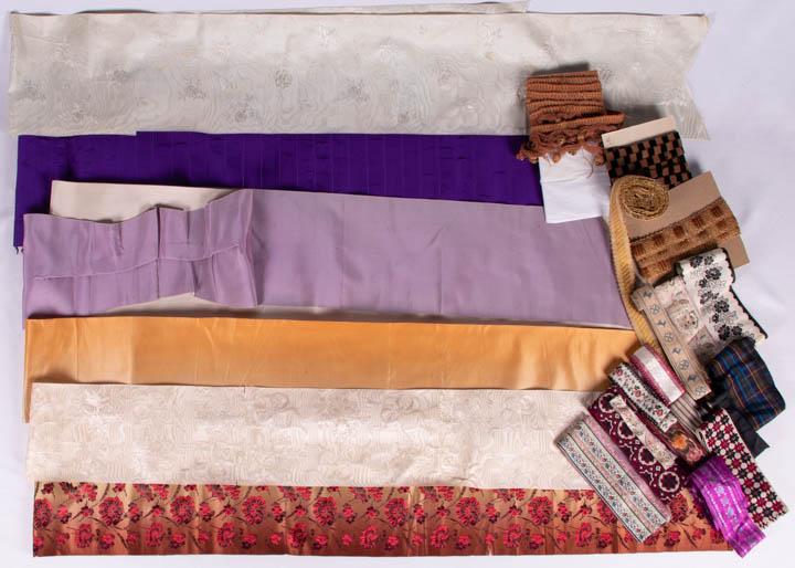 ASSORTMENT OF RIBBONS & TRIMS, 1890-1930: 2 lengths w/ warp & weft brocade in imitation of embroidery w/ rose motif on pressed moire ivory silk ground, Wd 5.5”, L 46.25” & Wd 7.5”, L 84.5” (scattered spot stains, pin holes, edges raw)